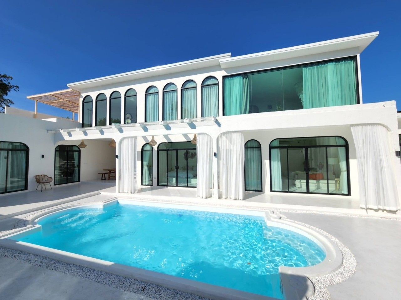 Exterior of White Coco V Pool Villa, พัทยากลาง-นาเกลือ. Modern white facade with arched windows and turquoise pool.
