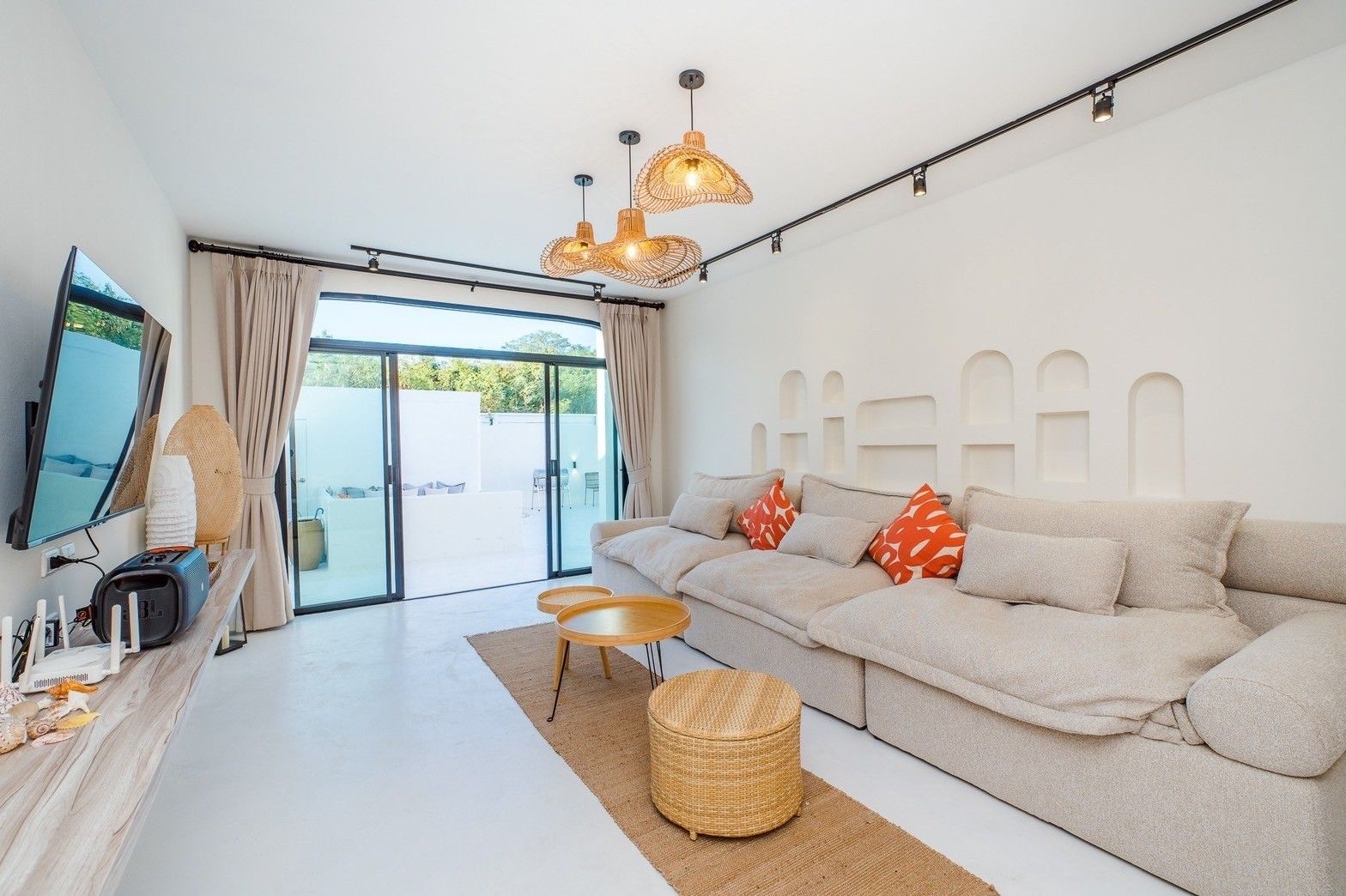 Living room at White Coco V Pool Villa, พัทยากลาง-นาเกลือ. Large sectional sofa, woven pendant lights, and sliding glass door