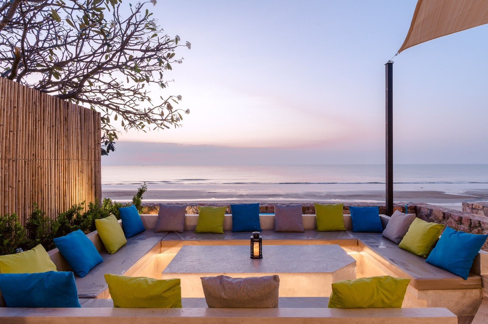 Beachfront lounge area at Beach Blanca IV pool villa in Cha-Am, Thailand. Colorful pillows and ocean view.
