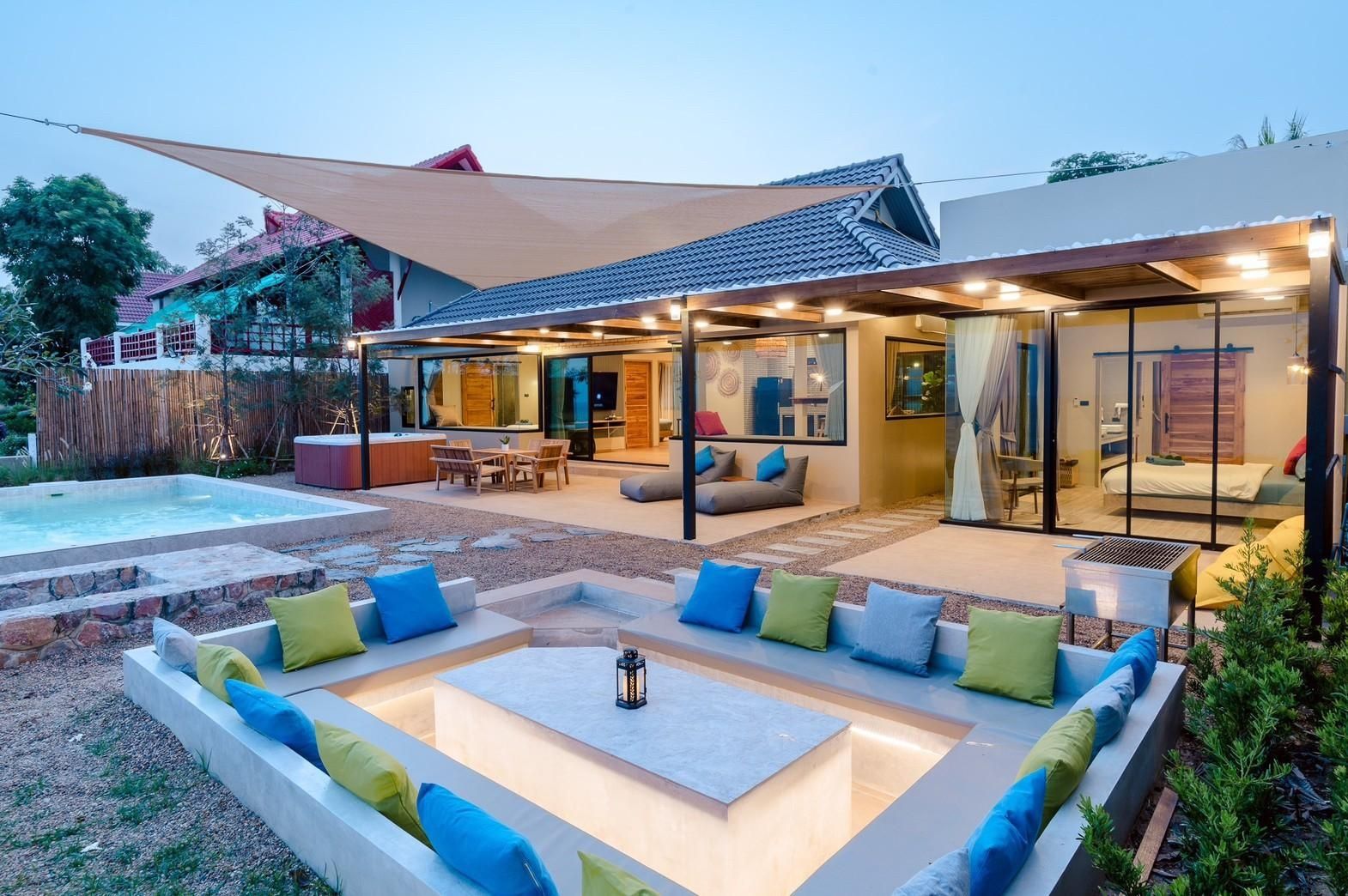 Outdoor sunken lounge pit with colorful cushions, private pool and hot tub at dusk — Beach Blanca IV Pool Villa