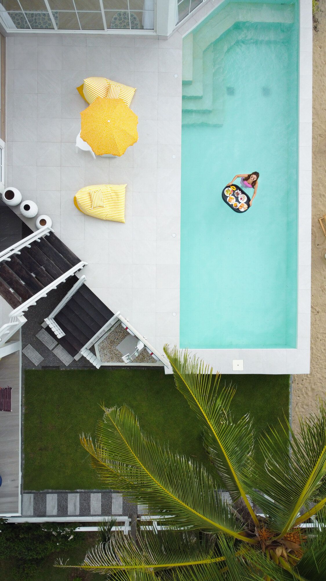Aerial view of a guest enjoying a floating breakfast in the pool at Coastal Calm IV Pool Villa, Cha-Am.