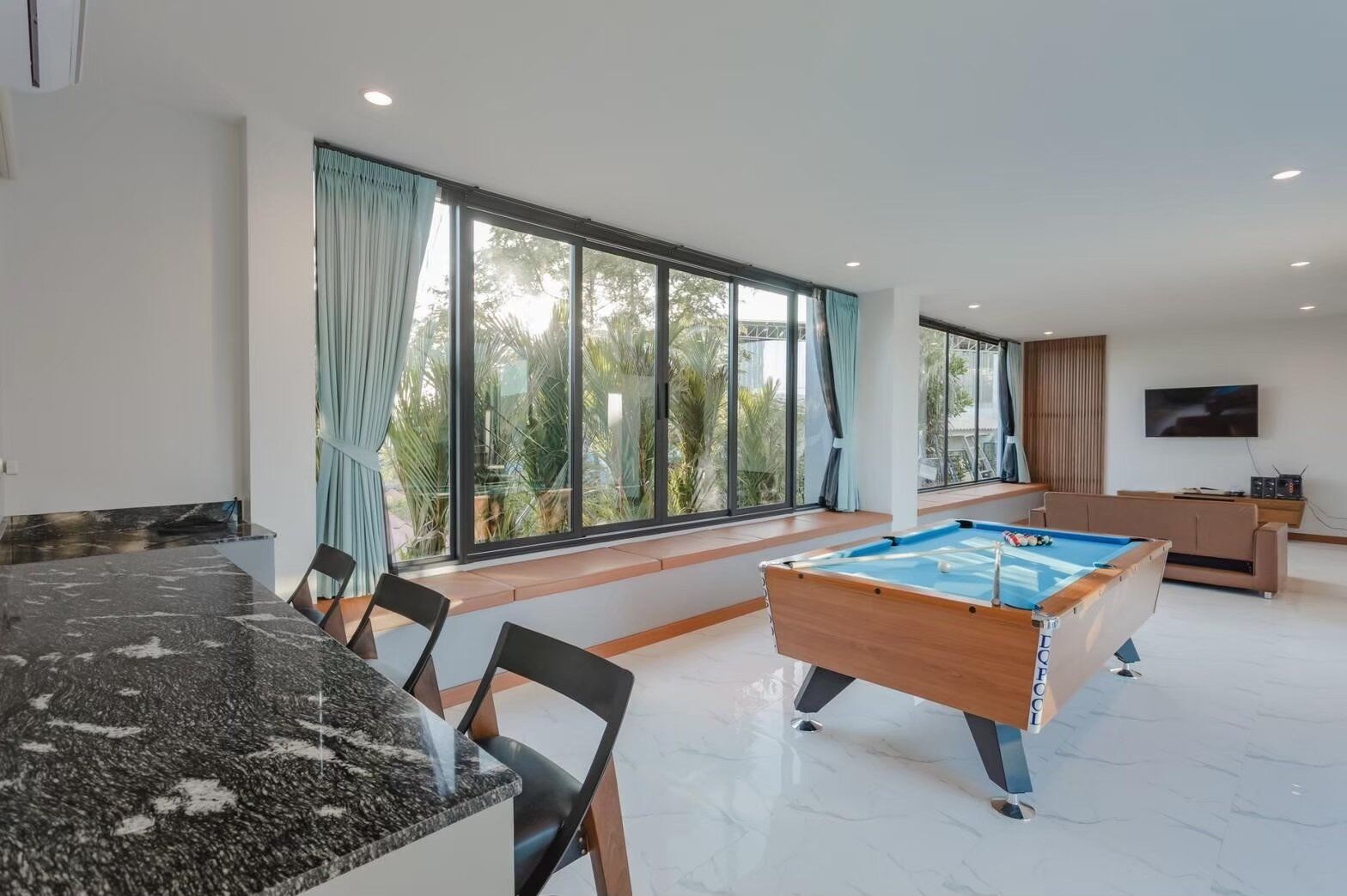 Exclusive Proud VII Villa in Hua Hin features a bright living area with a billiards table, bar seating, and large windows.