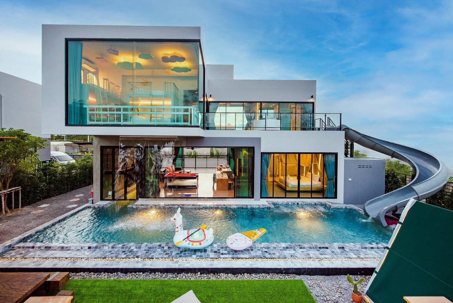 Holiday Sunset Villa IV pool view in Hua Hin. See the water slide, pool floats, and modern architecture.