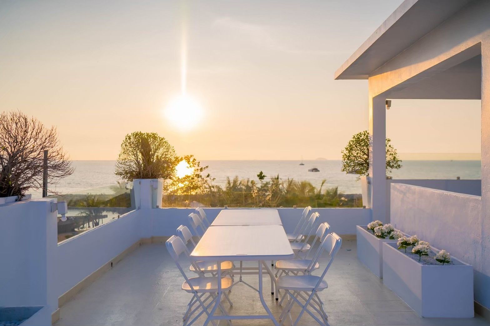 Rooftop dining at Royal Beach X Pool Villa, Pattaya. White table and chairs with ocean view at sunset.