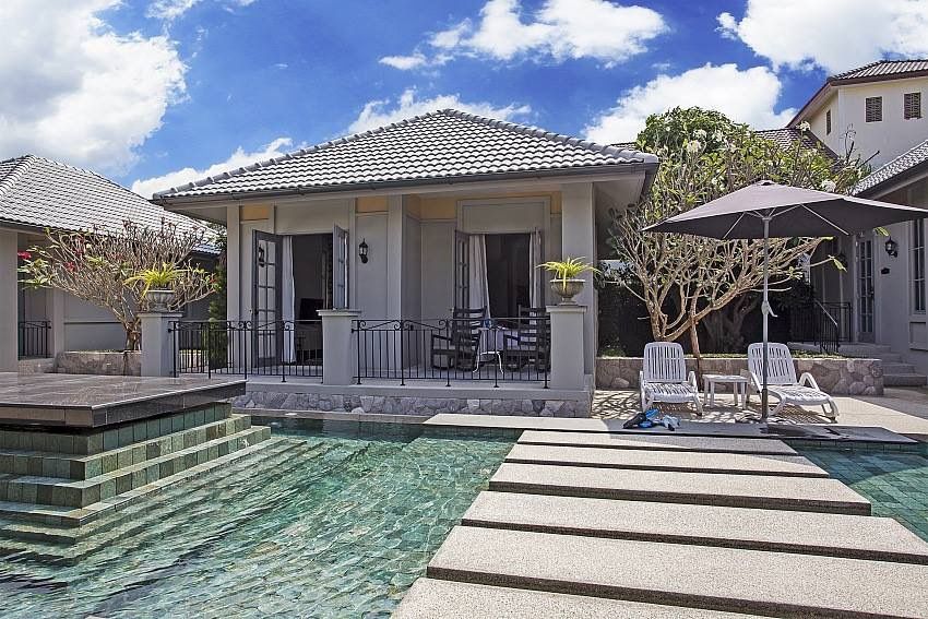 Exterior view of Sala Haven Nine Pool Villa in South Pattaya, featuring pool access from the villa and lounge chairs.