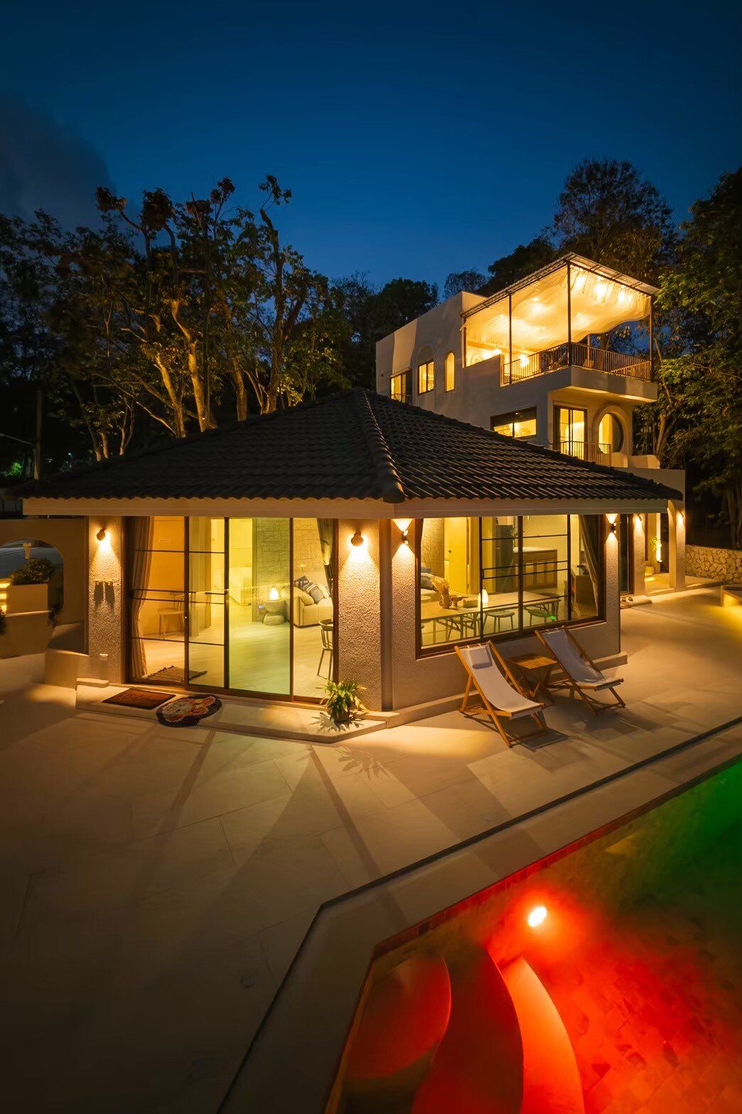 Sand Moment VI Pool Villa in Rayong at night, showcasing the illuminated exterior, pool deck, and lush trees.