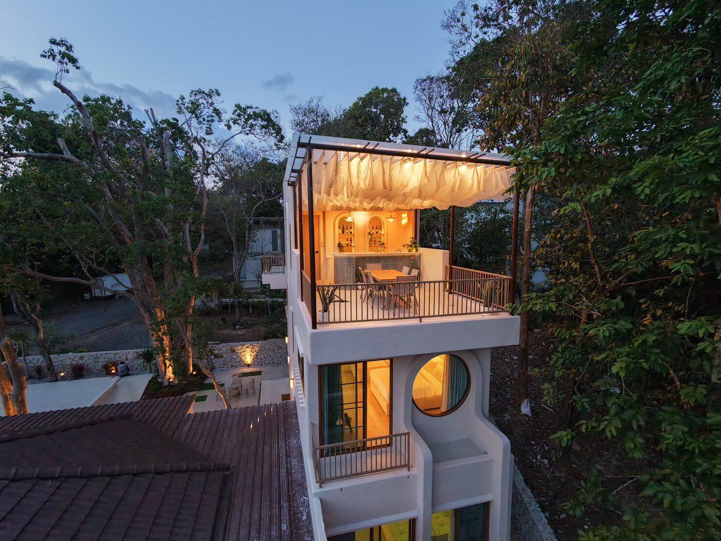 Aerial view of Sand Moment VI Pool Villa in Rayong at dusk, showcasing its multi-level design with a rooftop bar and balcony.