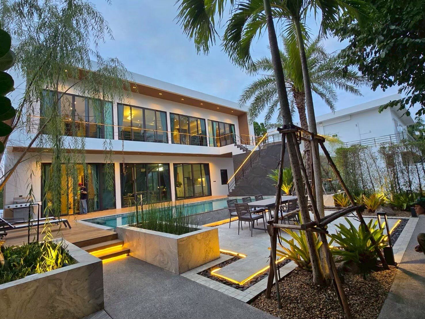 Exterior view of Sea Moment IV Pool Villa in Rayong at dusk, showcasing modern architecture and illuminated landscaping.