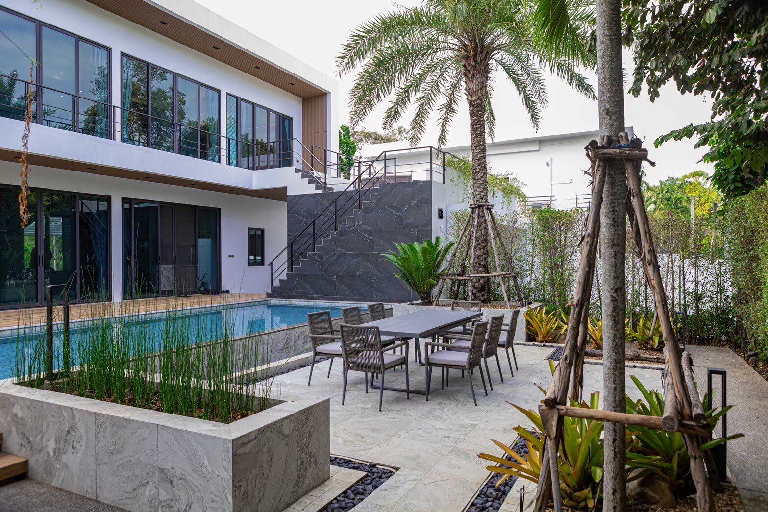 Sea Moment IV Pool Villa in Rayong features a refreshing swimming pool with an adjacent outdoor dining area for guests.