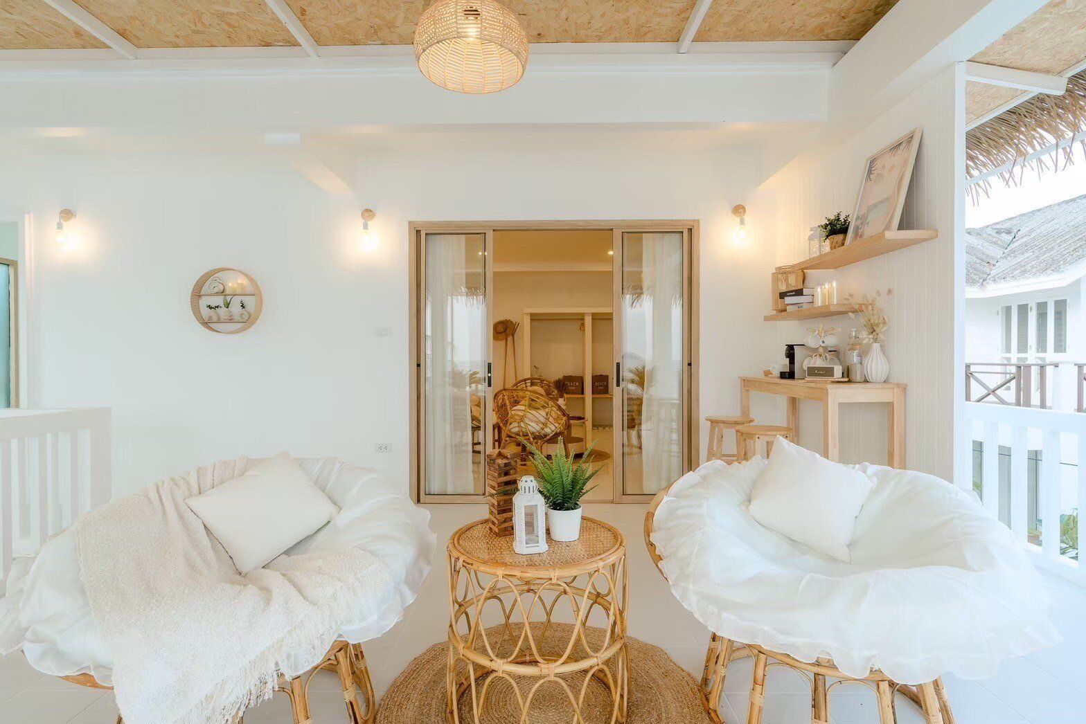 Cozy living area at Story II Pool Villa Hua-Hin with two rattan lounge chairs, a coffee table, and wooden decor.