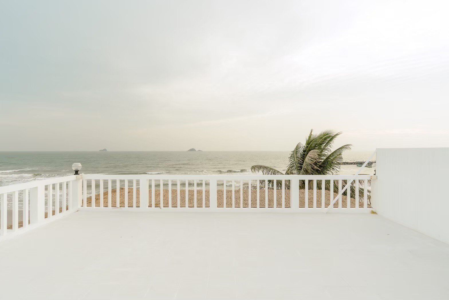 Rooftop terrace with white railing overlooking the ocean and beach at Story II Pool Villa Hua-Hin, Thailand.