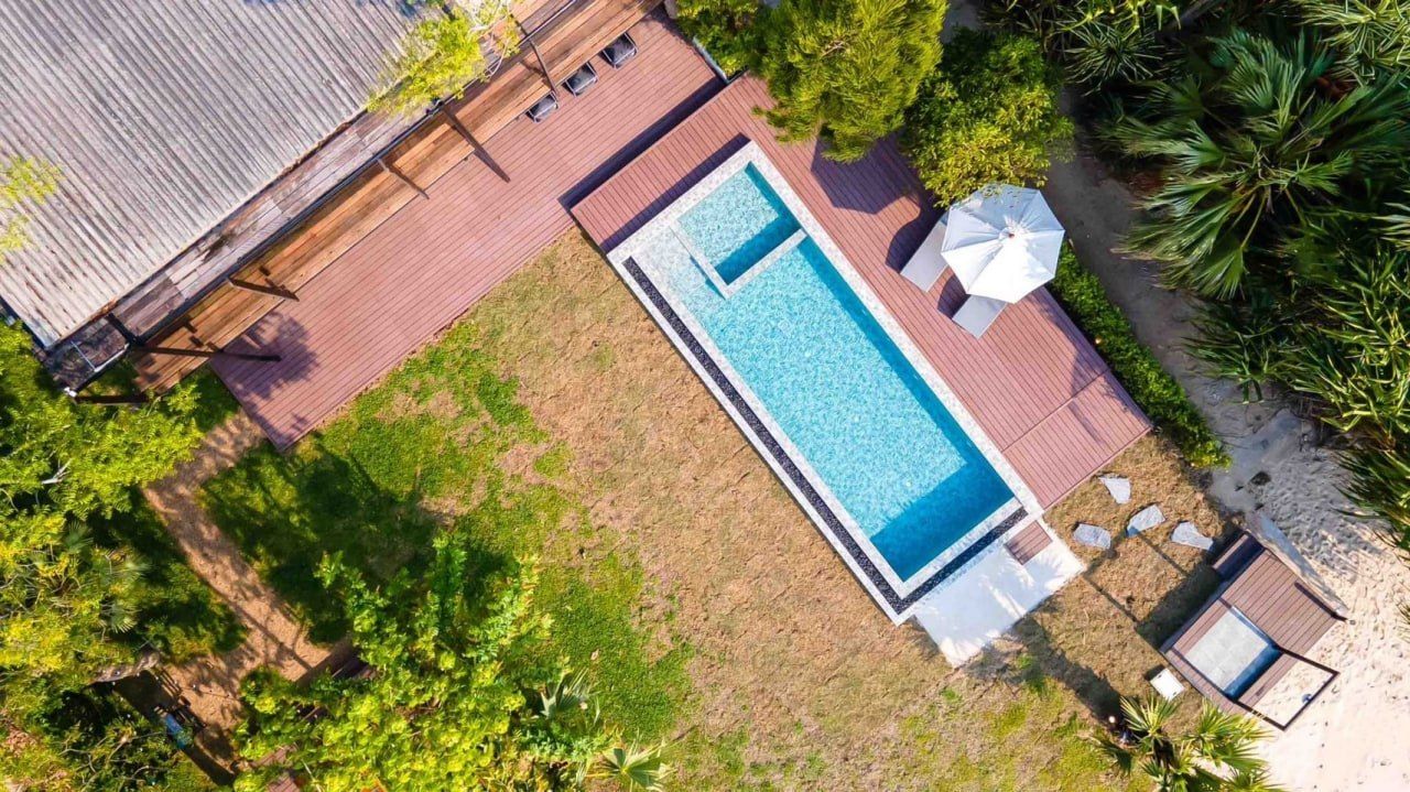 Aerial view of Studio Beachfront III Pool Villa in Cha-Am, showing the rectangular pool, wooden deck, and lush garden.