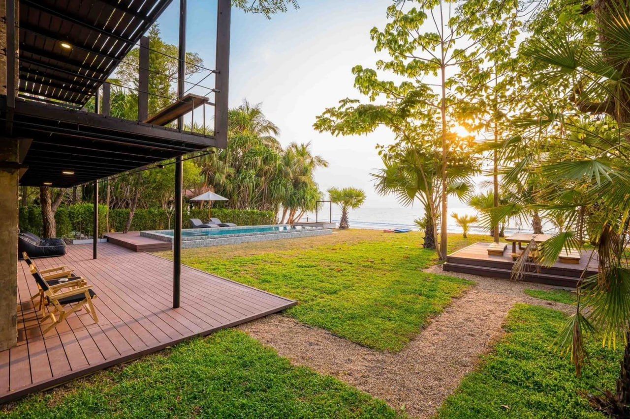 Studio Beachfront III Pool Villa in Cha-Am at sunset, showing the modern exterior, lush garden, pool, and direct beach access.