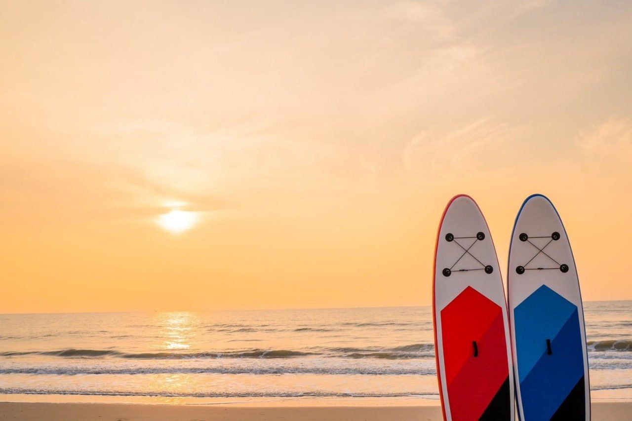 Two paddleboards on the sand at sunset, with the ocean in the background. Studio Beachfront III Pool Villa, Cha-Am.