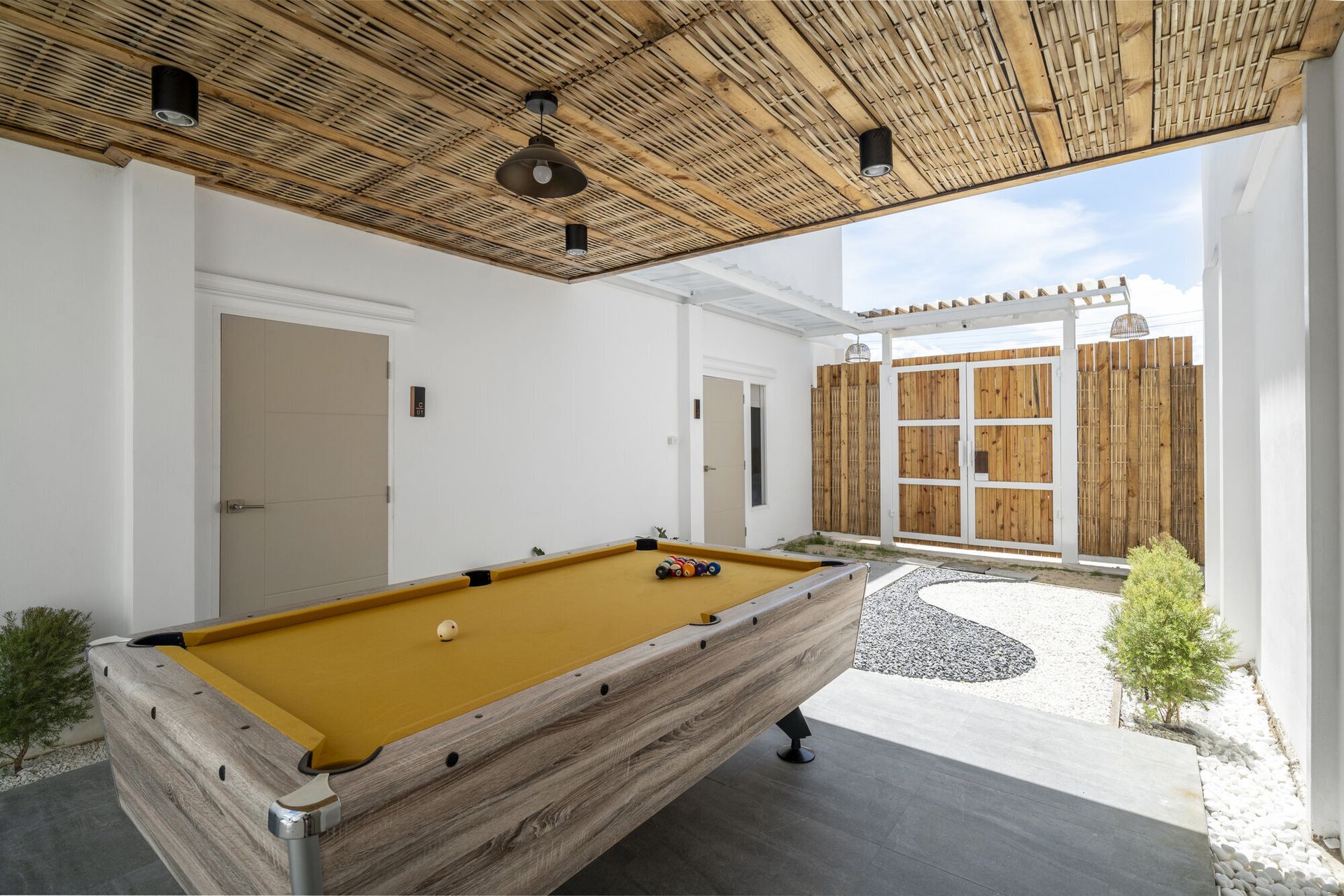 Outdoor billiards table with yellow felt under a bamboo ceiling at Talay Haus X Pool Villa, Cha-Am.