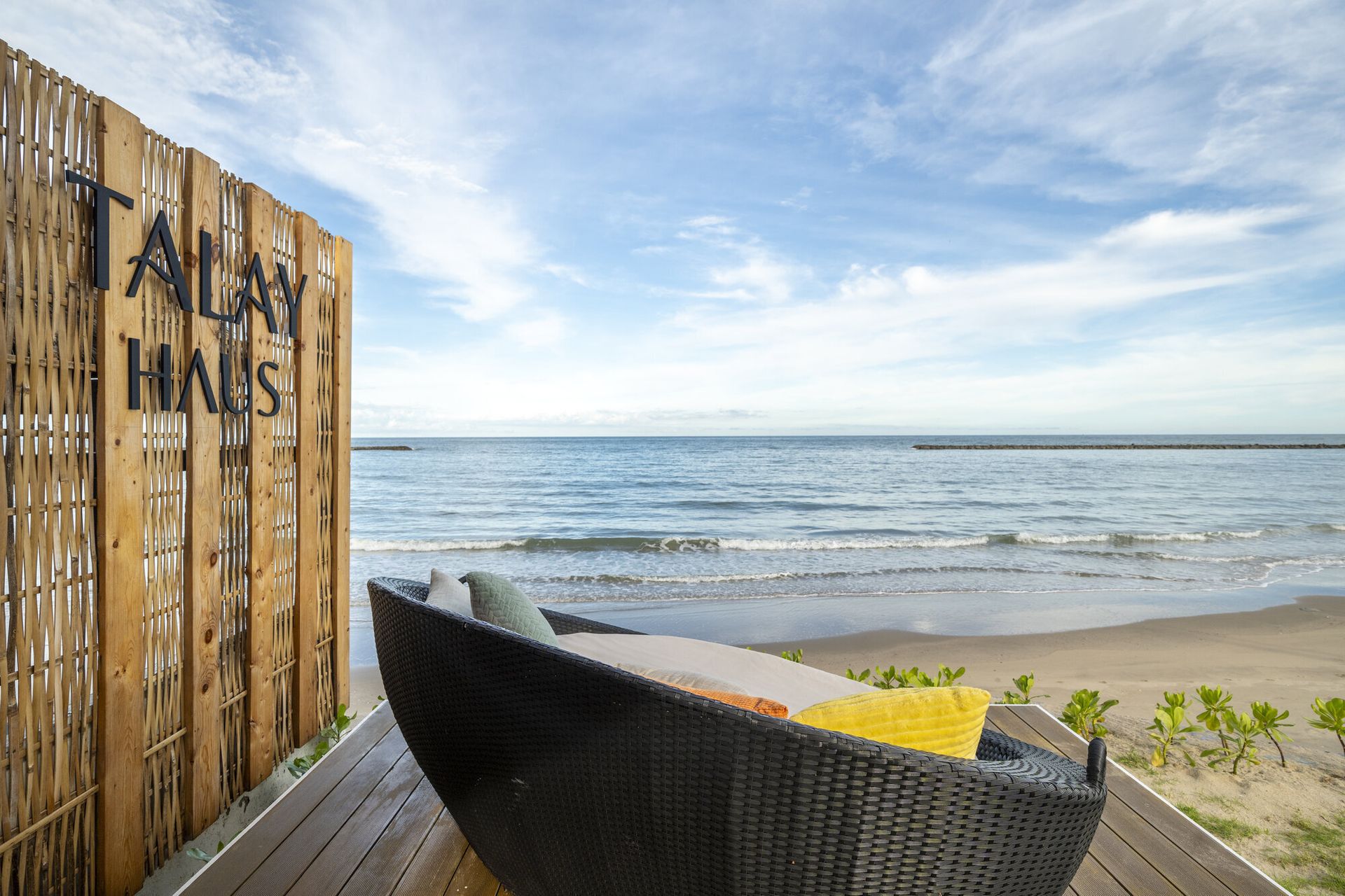 Relax on the beachfront daybed at Talay Haus X Pool Villa in Cha-Am, with stunning ocean views and a clear blue sky.