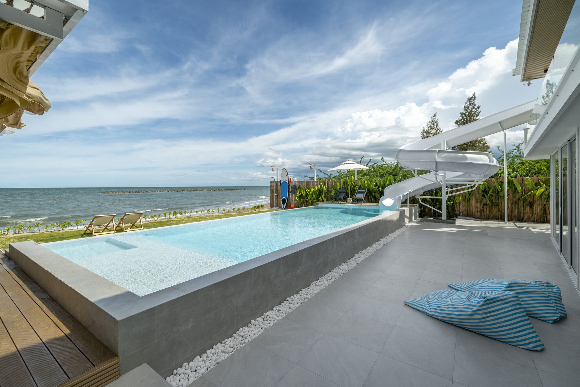 Talay Haus X Pool Villa in Cha-Am features a stunning oceanfront pool with a white water slide and sun loungers.