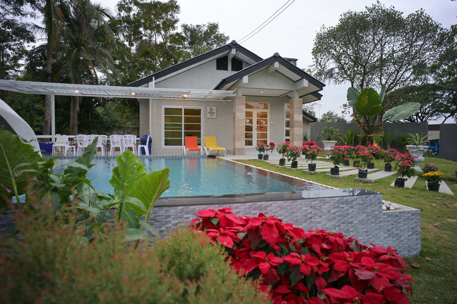 The Valley Khaoyai IX Villa exterior with a refreshing pool, lush red flowers, and green lawn in Khao Yai.