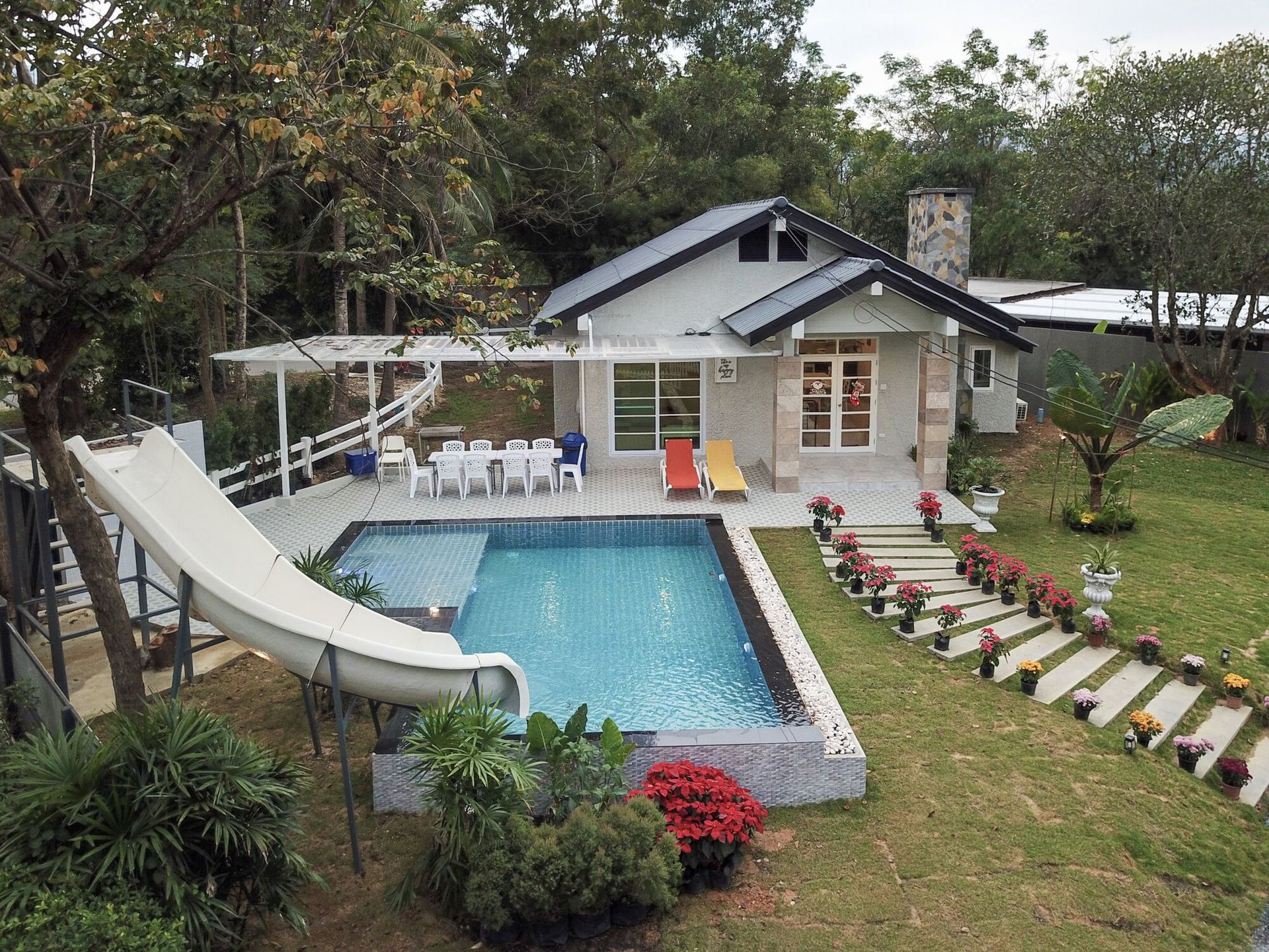 Aerial view of The Valley Khaoyai IX Villa, showcasing the private pool with a slide, outdoor dining, and lush garden.