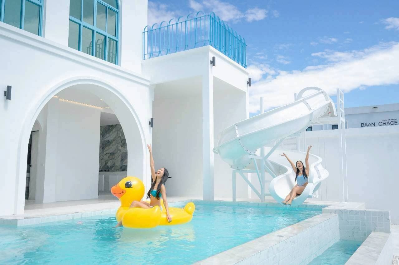 Guests enjoying the pool slide and a giant duck float at Tierra V Pool Villa, Pattaya. Perfect for family fun.