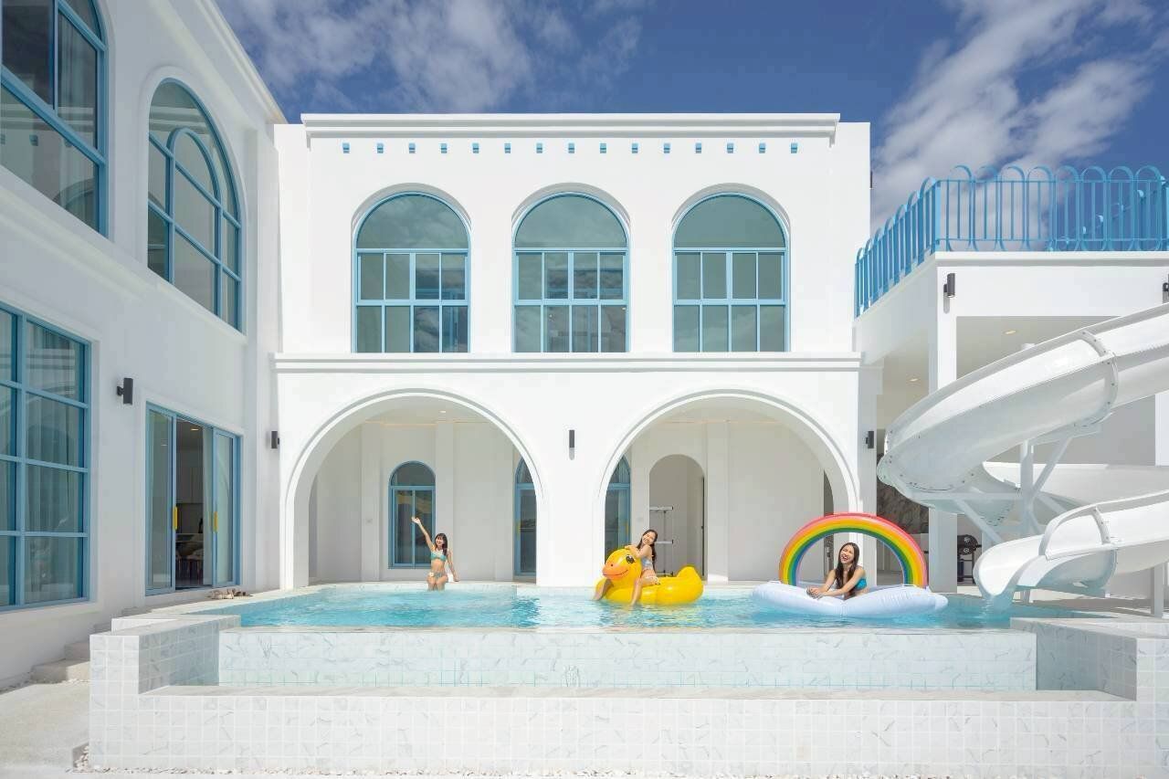 Guests enjoying the pool with a water slide and inflatables at Tierra V Pool Villa, Pattaya. Perfect for family fun.