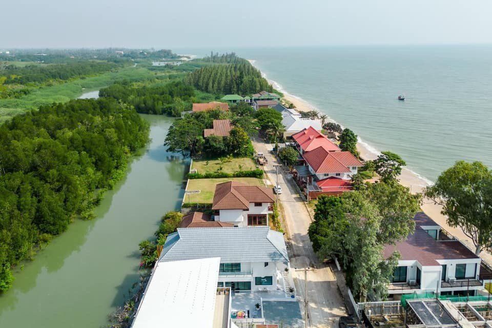 Aerial view of View Lay IV Pool Villa in Cha-Am, showing the beach, ocean, and river with lush greenery.