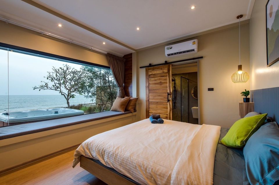 Bedroom at Beach Blanca IV Pool Villa, Cha-Am, featuring a king-size bed, window seat, and outdoor jacuzzi with sea views.