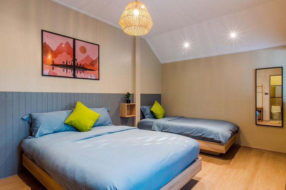 Bedroom at Beach Blanca IV Pool Villa, Cha-Am, with a queen bed and a single bed, blue linens, and vibrant wall art.