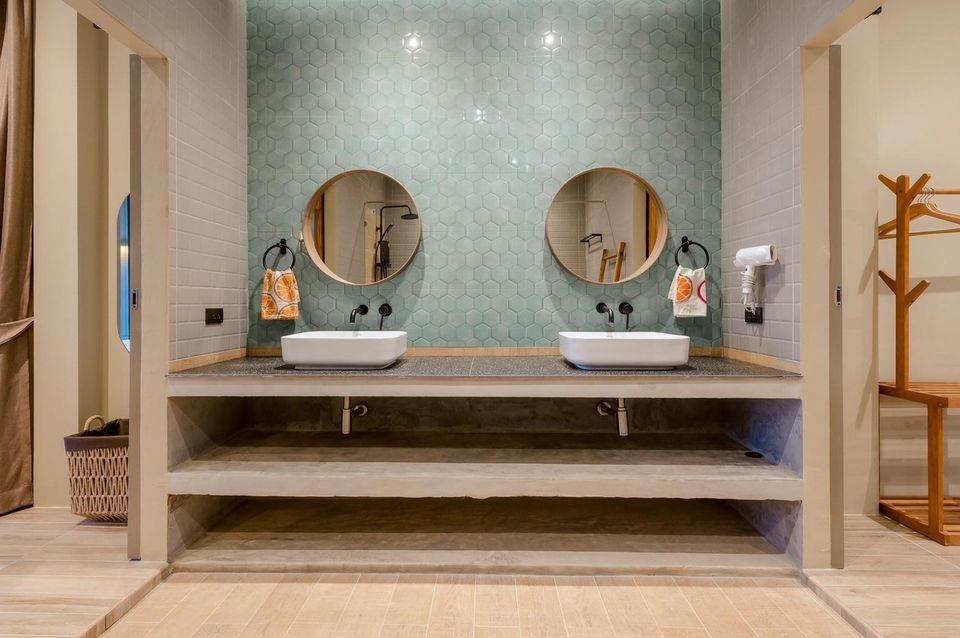 Modern bathroom with double vanity sinks, round mirrors, and hexagonal green tiles at Beach Blanca IV Pool Villa, Cha-Am.