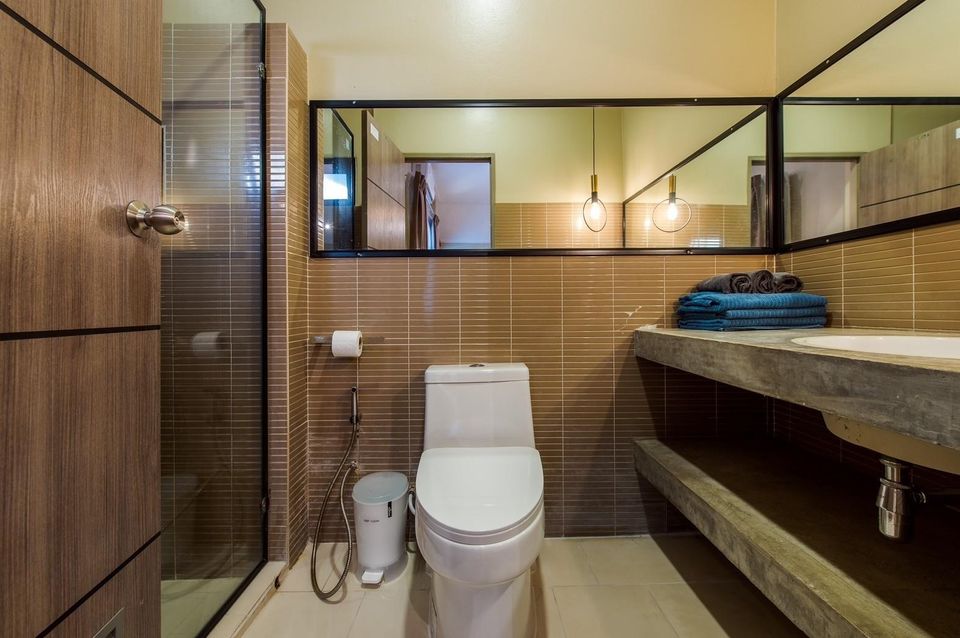 Modern bathroom with concrete vanity, toilet, and glass shower at Beach Blanca IV Pool Villa, Cha-Am.