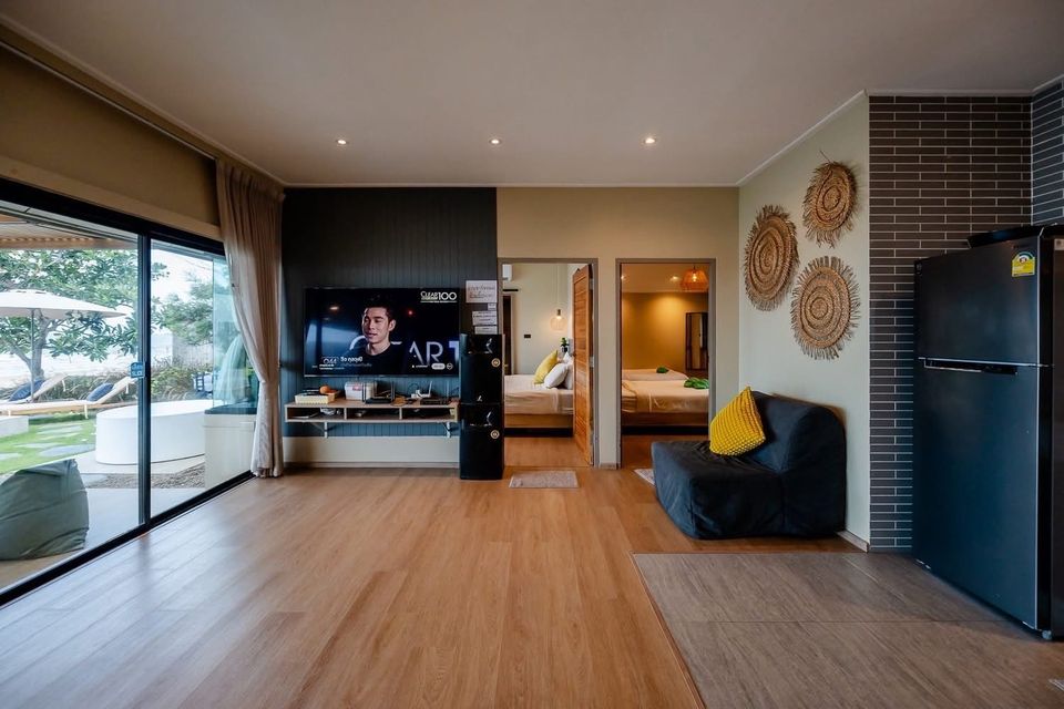 Open-plan villa living room with TV wall, two bedrooms and outdoor garden view — Beach Blanca IV Pool Villa