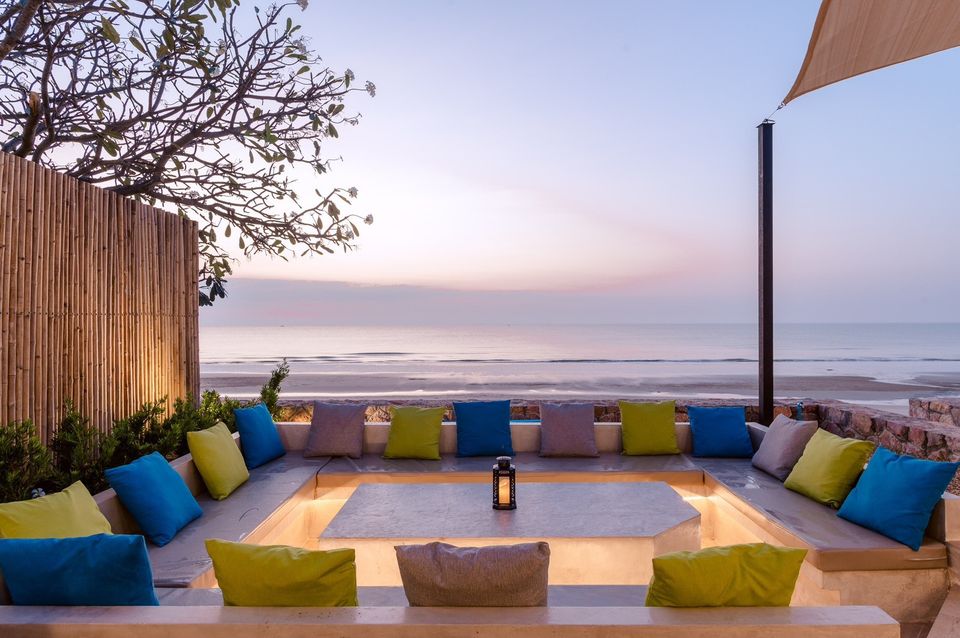 Beachfront lounge area at Beach Blanca IV pool villa in Cha-Am, Thailand. Colorful pillows and ocean view.