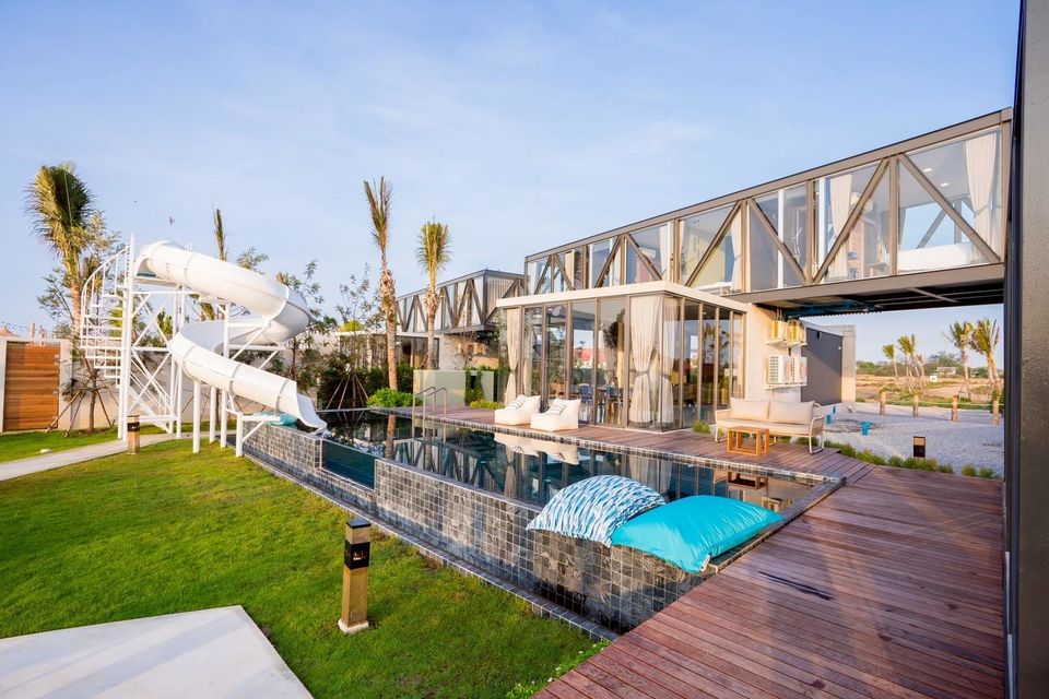 Beyond V Pool Villa pool and waterslide in หาดปึกเตียน-ชะอำ. Modern design with glass walls and wooden deck.