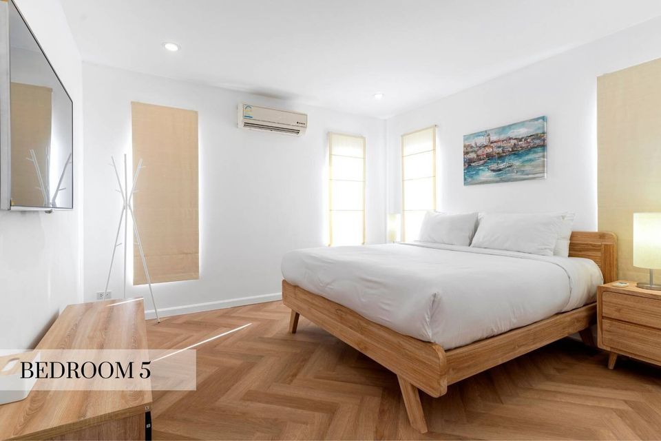 Bright bedroom 5 at Caribbean V Pool Villa, Hua Hin, featuring a comfortable king-size bed with white linens and a vibrant painting.