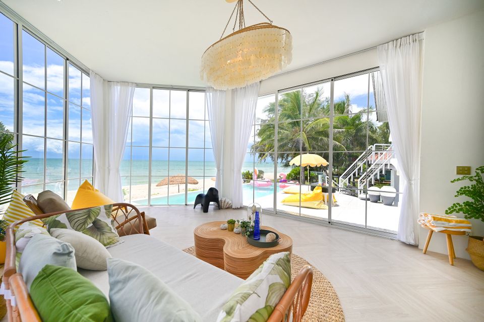 Bright living room at Coastal Calm IV Pool Villa, Cha-Am, with ocean views, a comfortable sofa, and unique shell chandelier.
