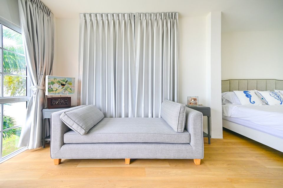 Bright bedroom at Coastal Calm IV Pool Villa, Cha-Am, featuring a grey daybed, window with garden view, and bed with seahors