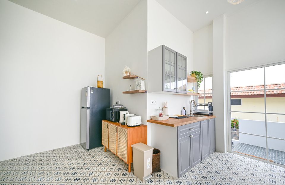Bright, modern compact kitchen at Coastal Calm IV Pool Villa, Cha-Am, featuring grey cabinets, wooden countertops, and patte