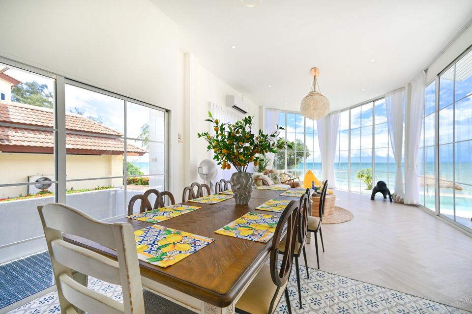Spacious dining area with a long wooden table, lemon-themed placemats, and stunning ocean views at Coastal Calm IV Pool Vill