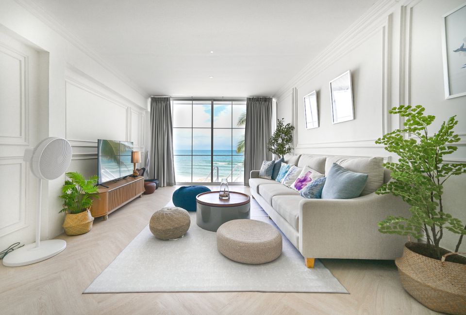 Bright living room at Coastal Calm IV Pool Villa, Cha-Am, with a comfortable sofa, TV, and stunning ocean views.