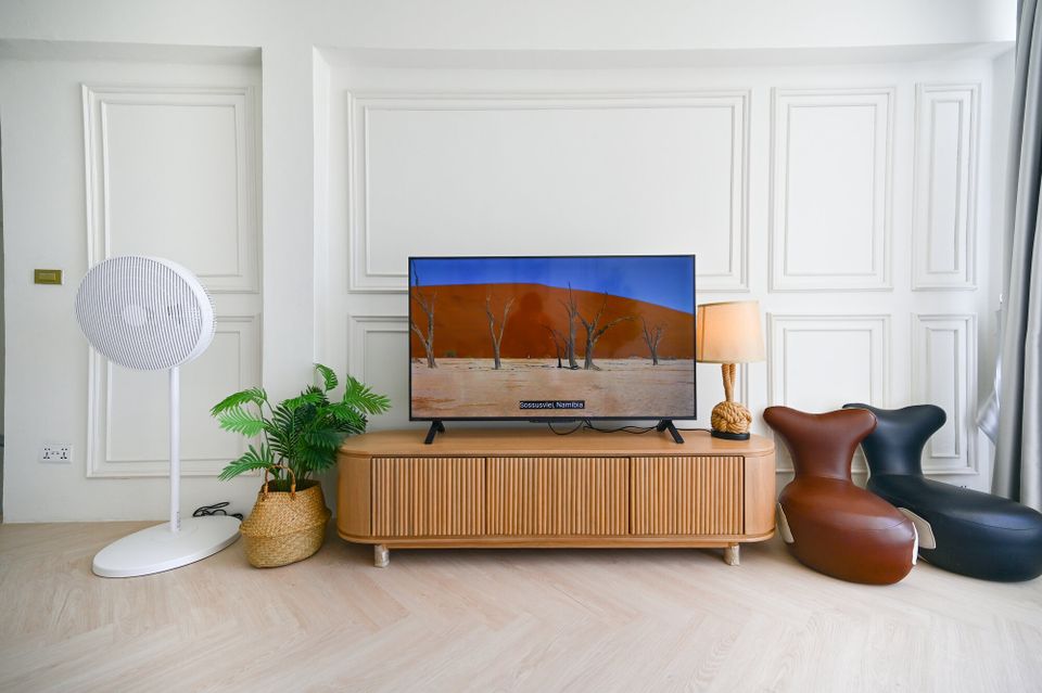 Modern living area at Coastal Calm IV Pool Villa, Cha-Am, featuring a large TV, stylish wooden console, and unique lounge ch