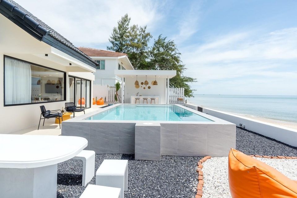 Costa IV Beachfront Pool Villa in ชะอำ เพชรบุรี features a pool with a bar overlooking the ocean. Outdoor seating and beanbag
