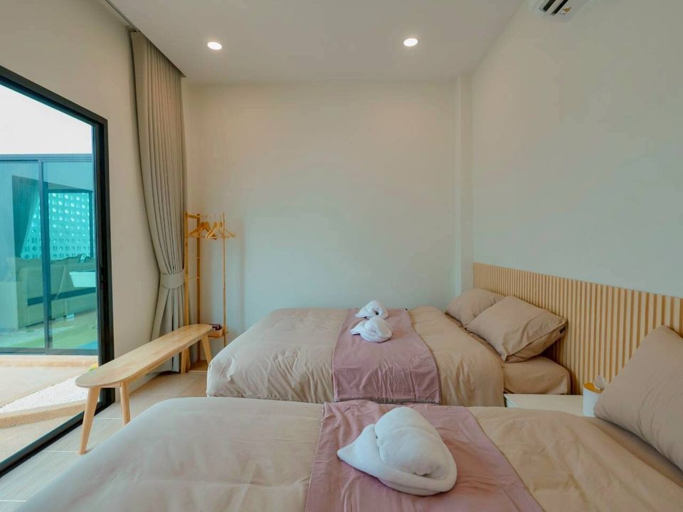 Bright bedroom at Darlington IV Pool Villa, Cha-Am, featuring two comfortable twin beds with fresh linens and a balcony access.