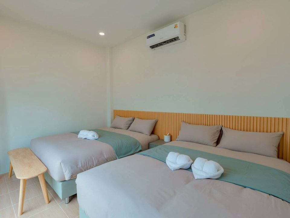 Two comfortable beds with light grey and mint green bedding in a bedroom at Darlington IV Pool Villa, Cha-Am.