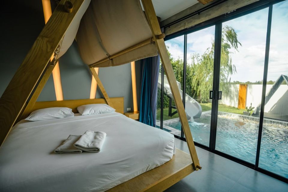 Bedroom at Holiday Sunset Villa IV, Hua Hin, featuring a unique canopy bed and direct views of the pool with a waterslide.