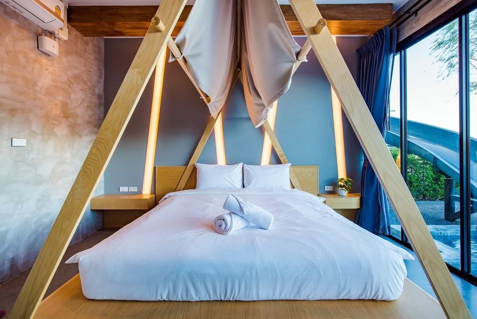 A modern bedroom at Holiday Sunset Villa IV in Hua Hin, featuring a king-size bed with a unique wooden canopy frame.