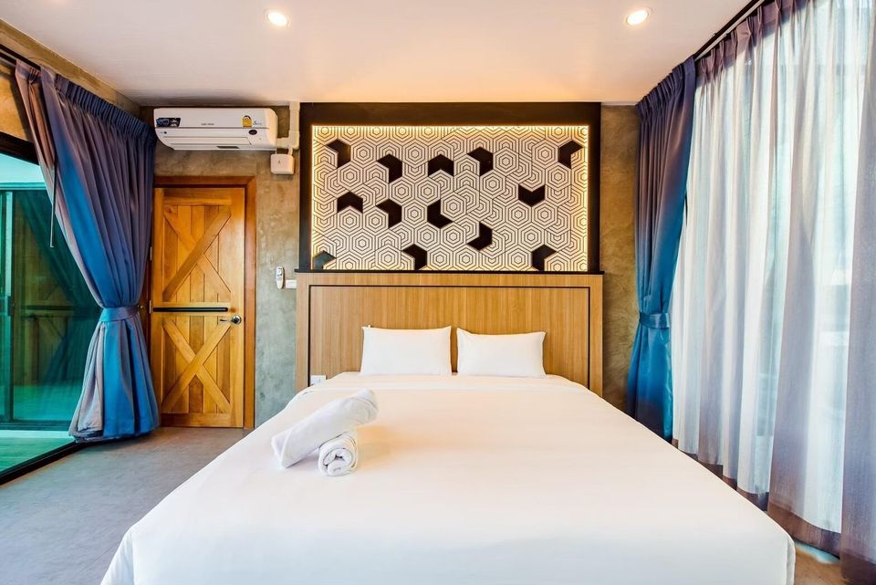 A king-size bed with white linens and a unique geometric headboard in a bedroom at Holiday Sunset Villa IV, Hua Hin.