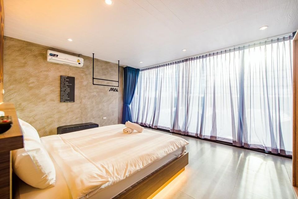 A modern king-size bed with white linens and under-bed lighting in a bedroom at Holiday Sunset Villa IV, Hua Hin.