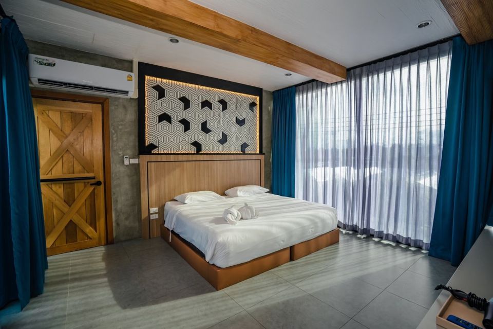 Modern king-size bed with white linens and patterned headboard in a bedroom at Holiday Sunset Villa IV, Hua Hin.