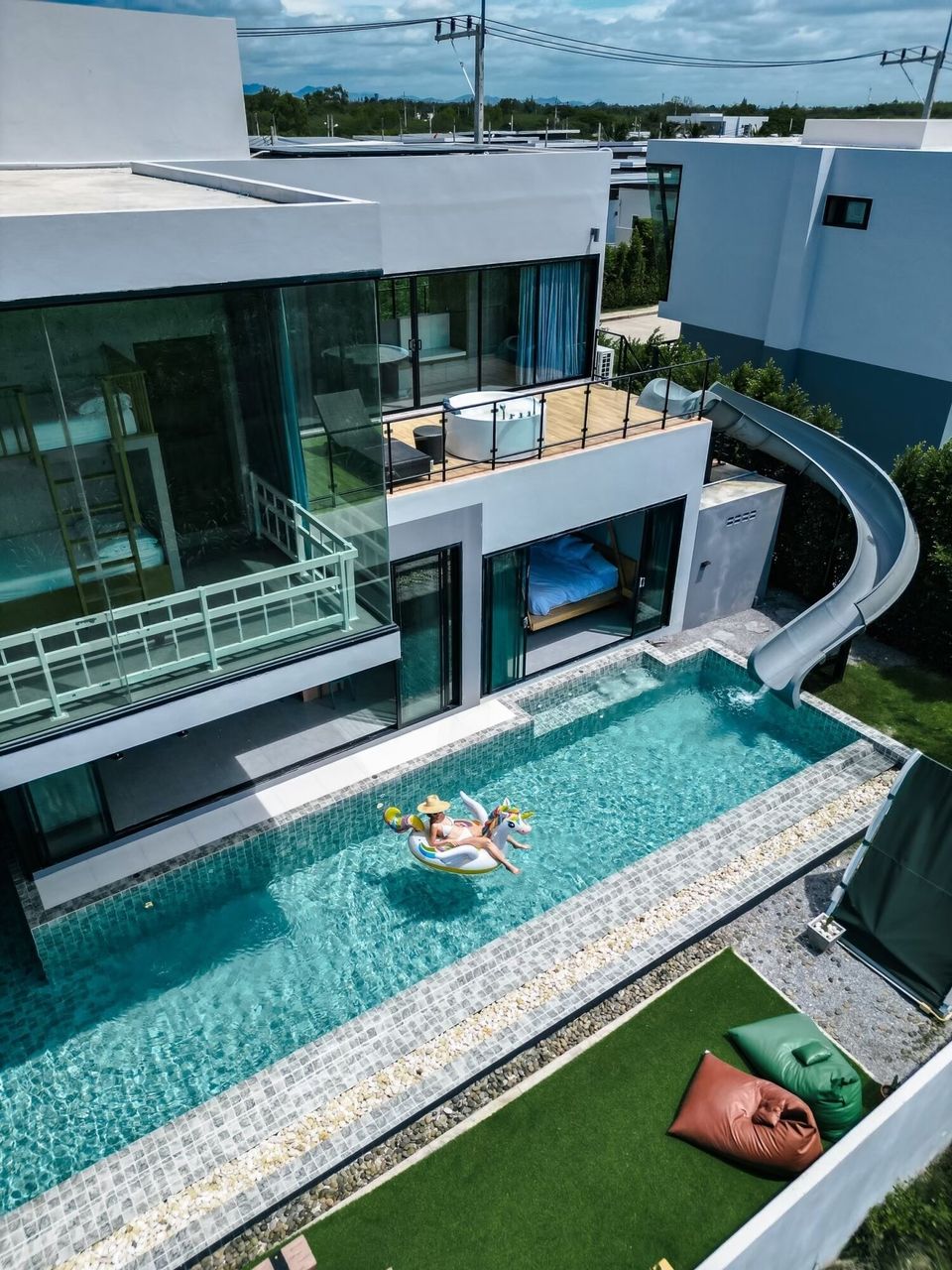 Aerial view of Holiday Sunset Villa IV in Hua Hin, showing the pool, water slide, and modern architecture.