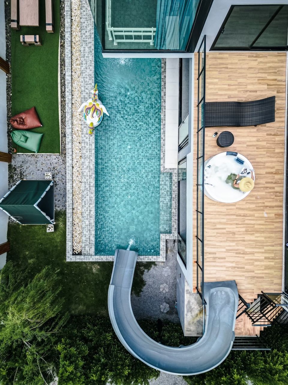 Aerial view of Holiday Sunset Villa IV in Hua Hin, featuring a long swimming pool with a water slide and a bubbling jacuzzi.